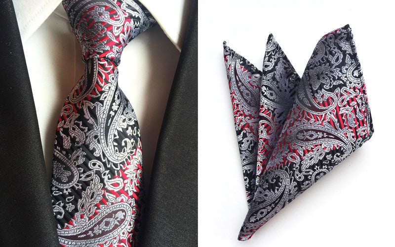 A stylish black and red paisley tie paired with a classic black and white pocket square, showcasing elegant fashion details.