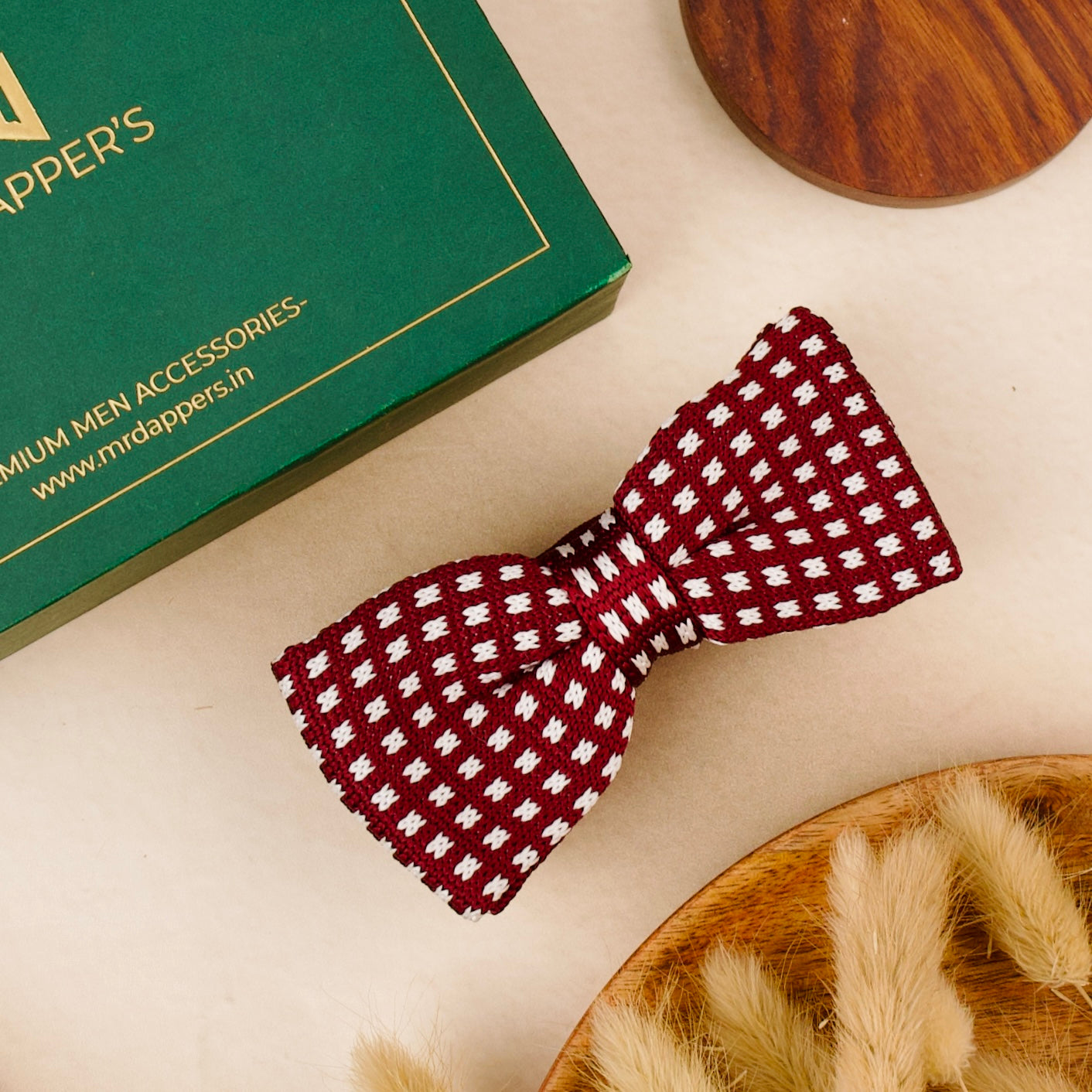 A vibrant red and white bow tie is placed on a table next to a box of mr dappers , adding a whimsical touch to the setting.