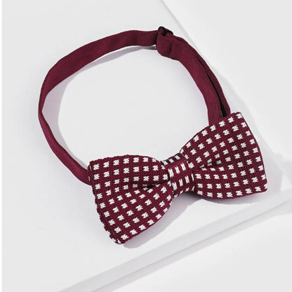 A vibrant red and white bow tie is placed on a table next to a box , adding a whimsical touch to the setting.