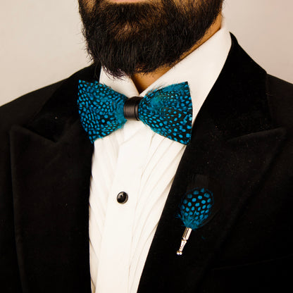 A blue and black feather bow tie and pin set next to a green box labeled "Mr. Dapper's.
