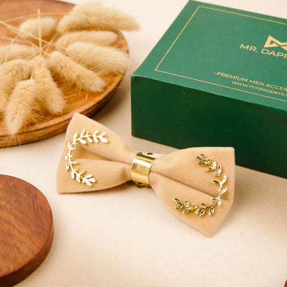 A bow tie adorned with gold leaves, elegantly displayed in a green box.