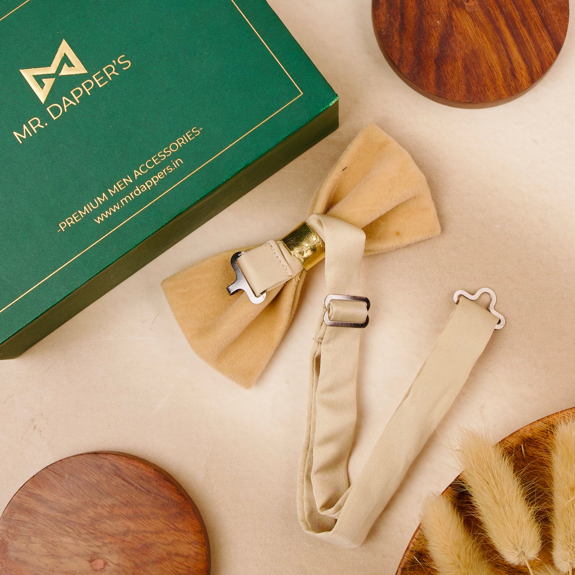 A bow tie adorned with gold leaves, elegantly displayed in a green box.