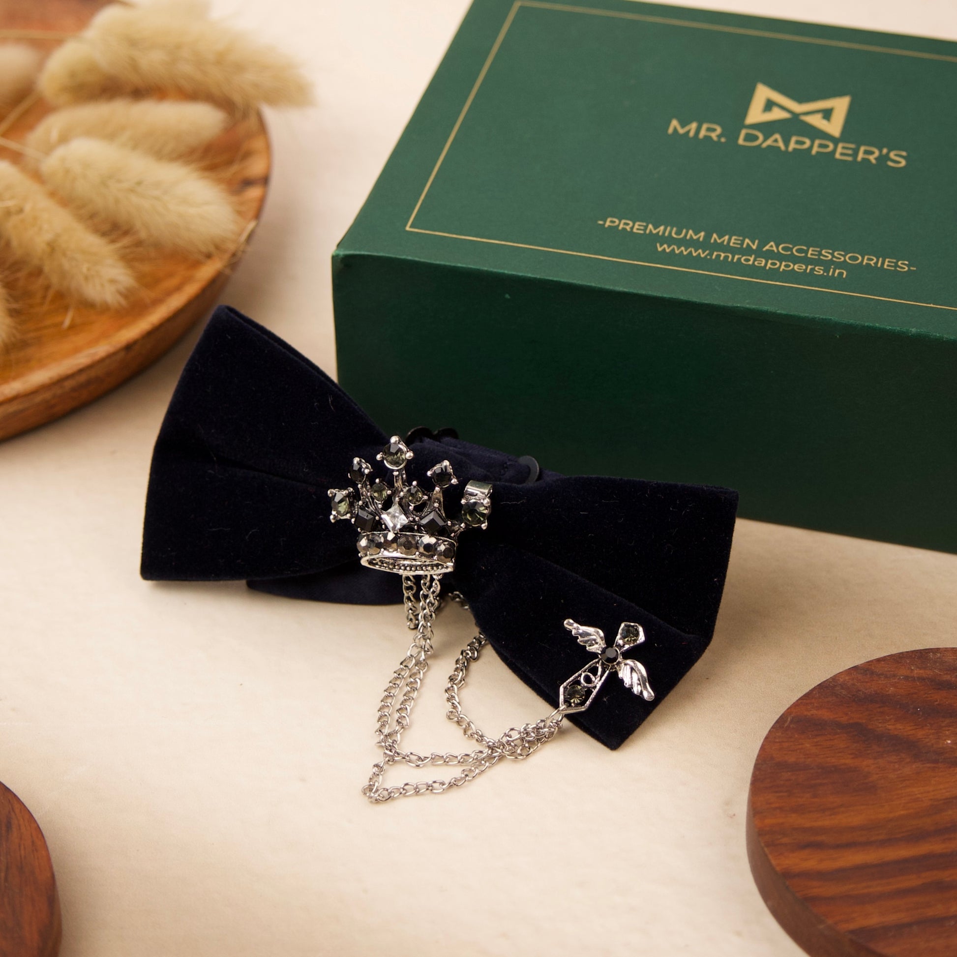 A black velvet bow tie adorned with a silver chain and a decorative flower, showcasing elegance and sophistication.