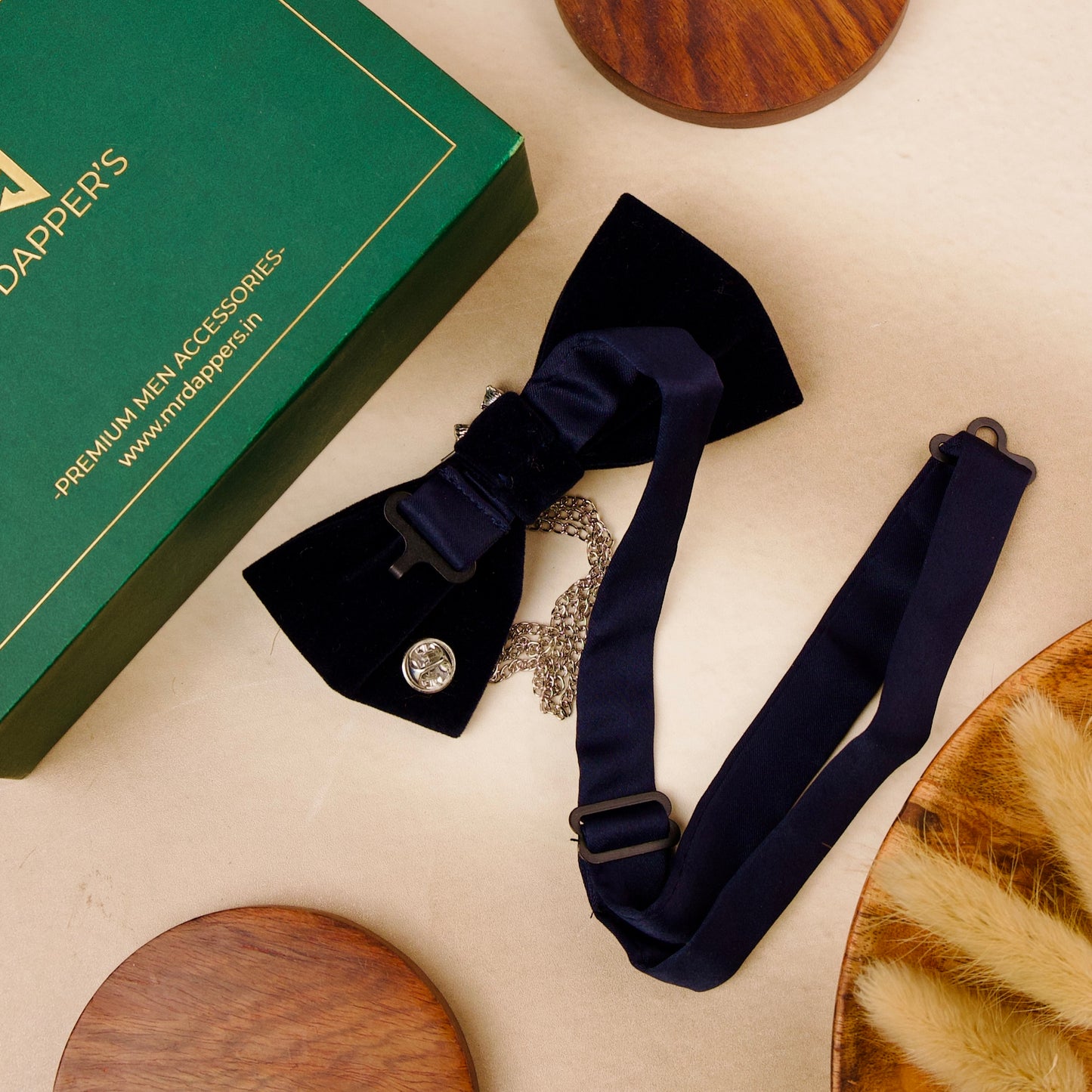 A black velvet bow tie adorned with a silver chain and a decorative flower, showcasing elegance and sophistication.
