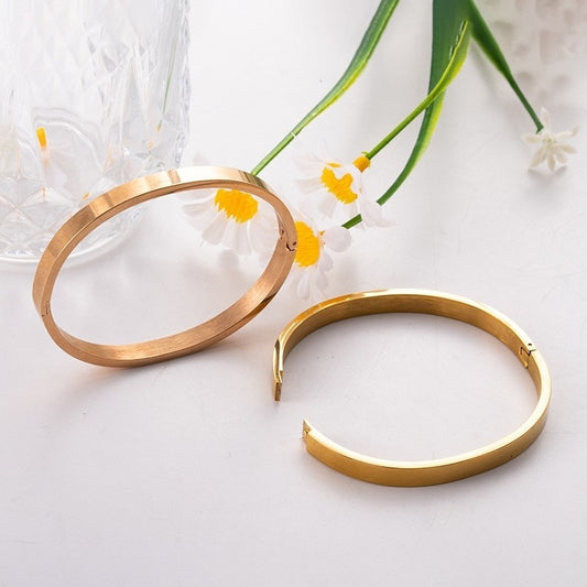  A simple gold bang bracelet displayed on a clean white background, highlighting its elegant design and shine.