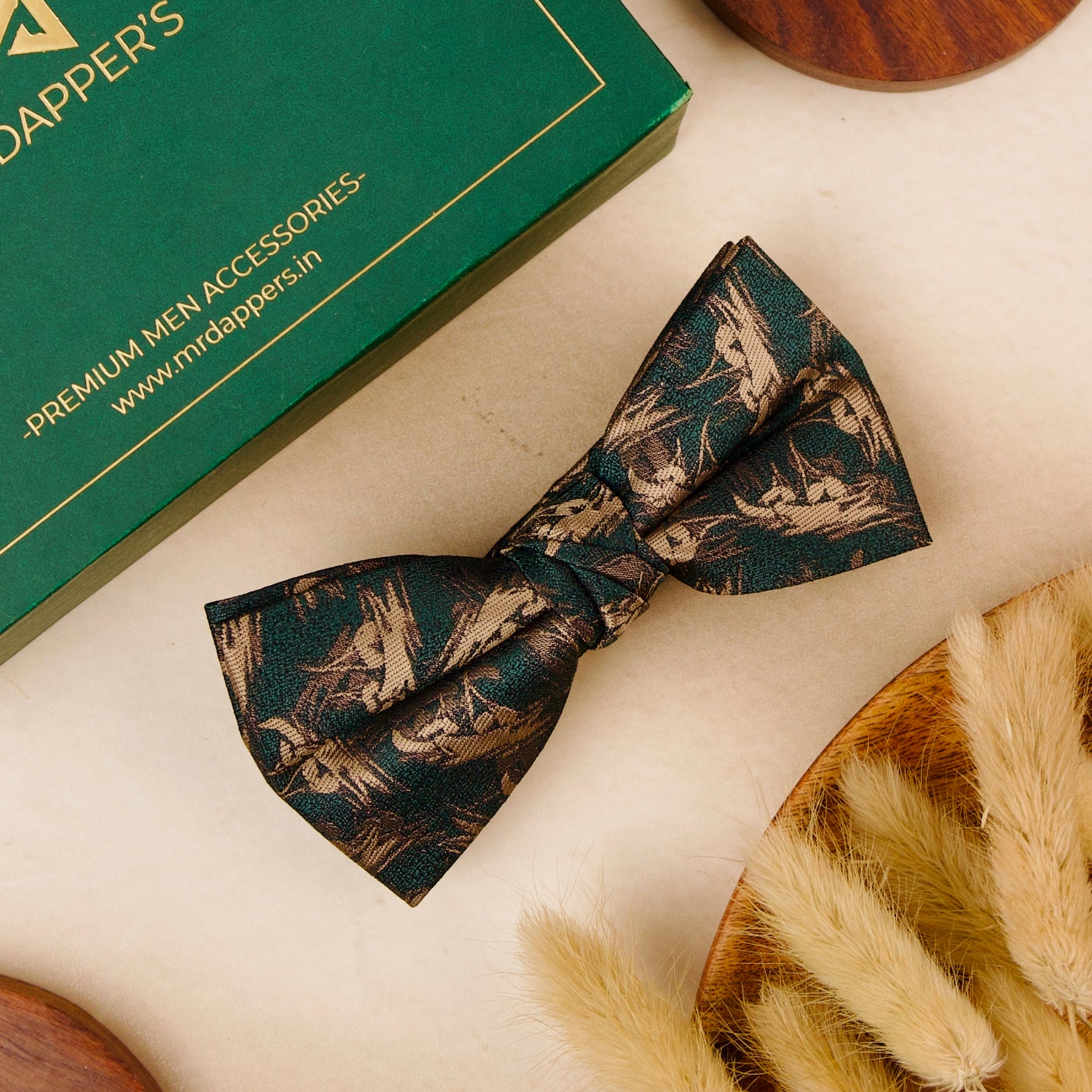 A green bow tie featuring an intricate green and gold pattern