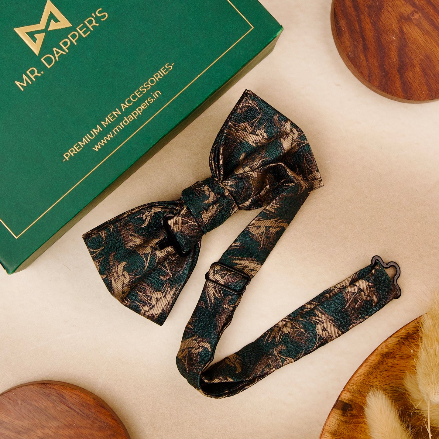 A green bow tie featuring an intricate green and gold pattern