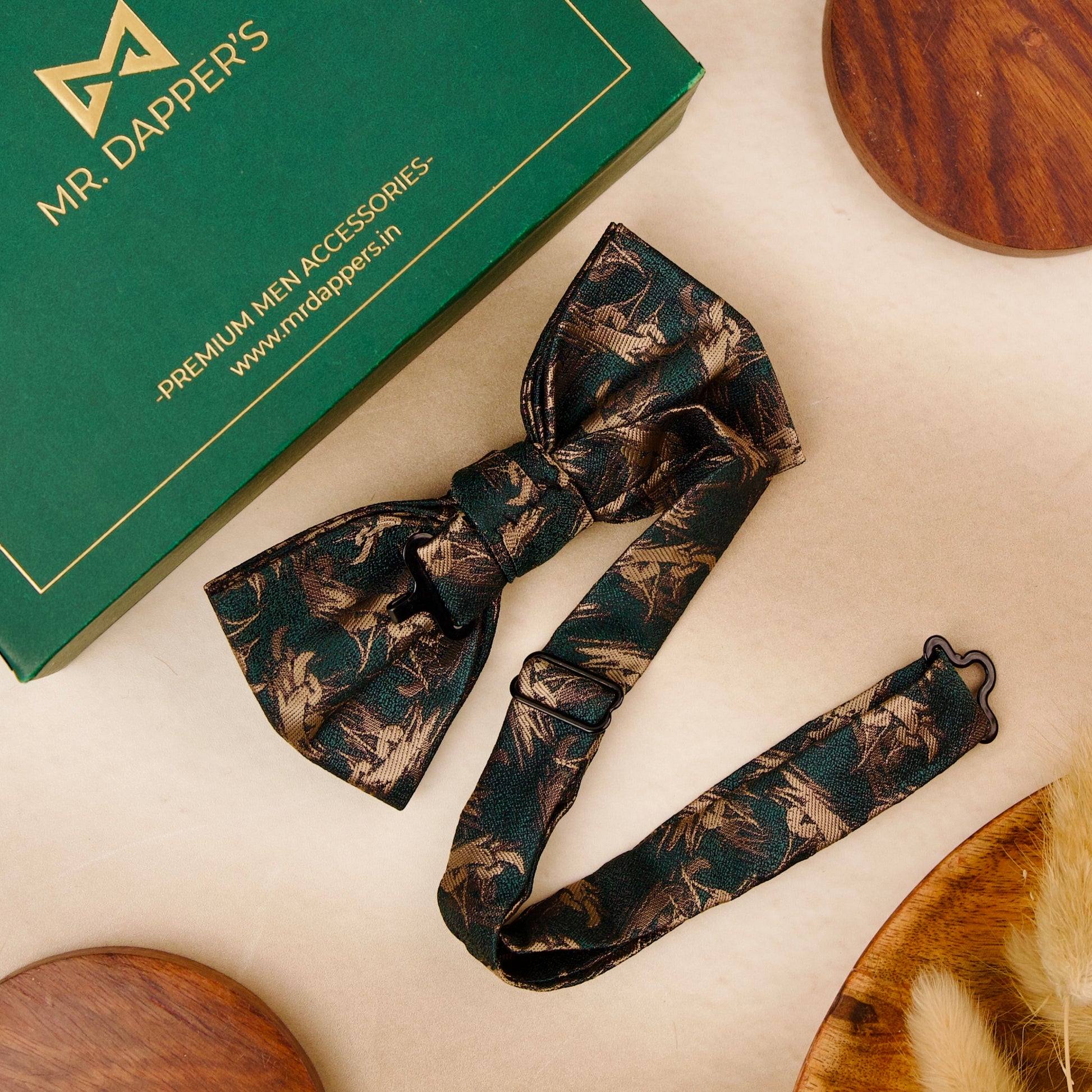 A green bow tie featuring an intricate green and gold pattern