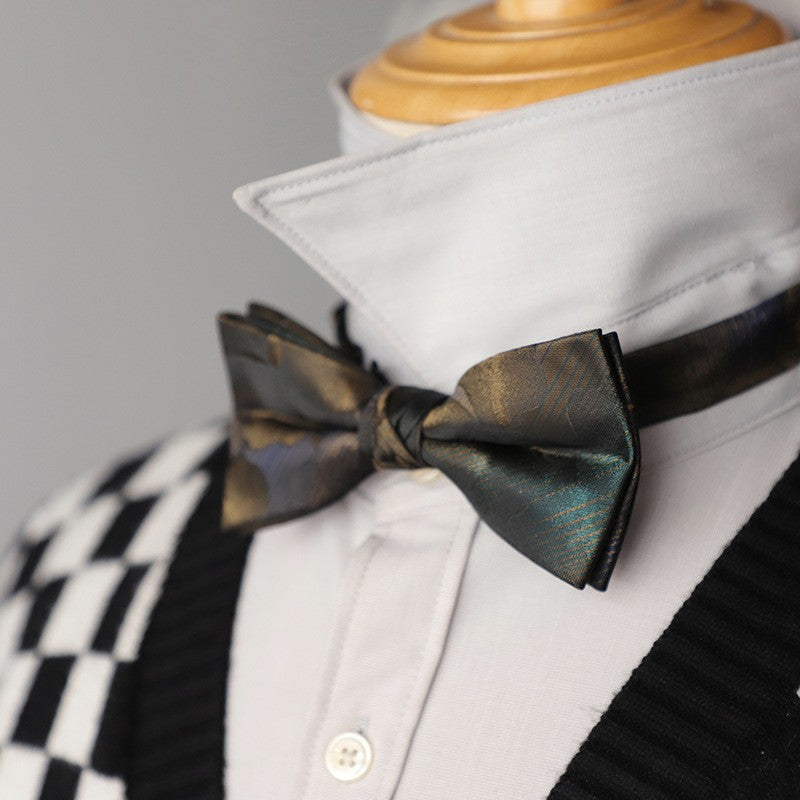 A green bow tie featuring an intricate green and gold pattern