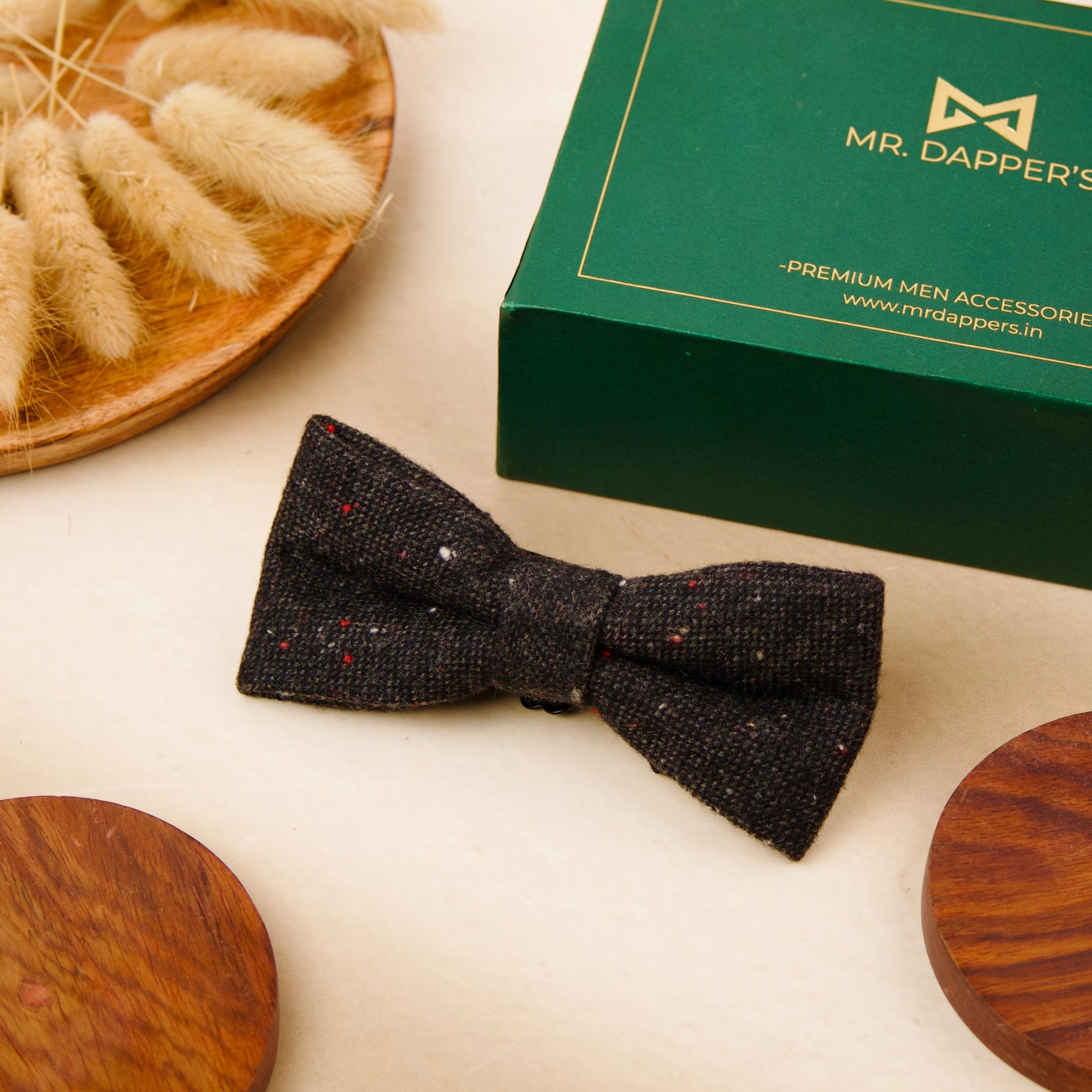  A black bow tie elegantly placed beside a polished wooden box, showcasing a classic and sophisticated arrangement.
