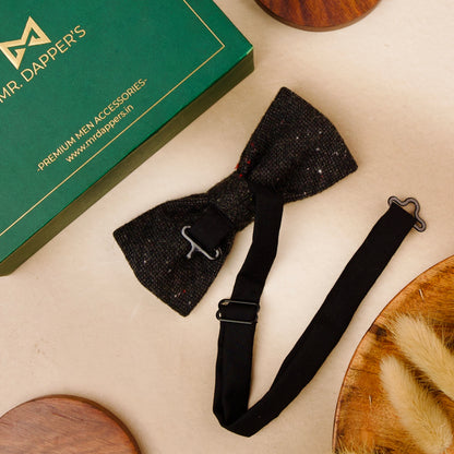  A black bow tie elegantly placed beside a polished wooden box, showcasing a classic and sophisticated arrangement.
