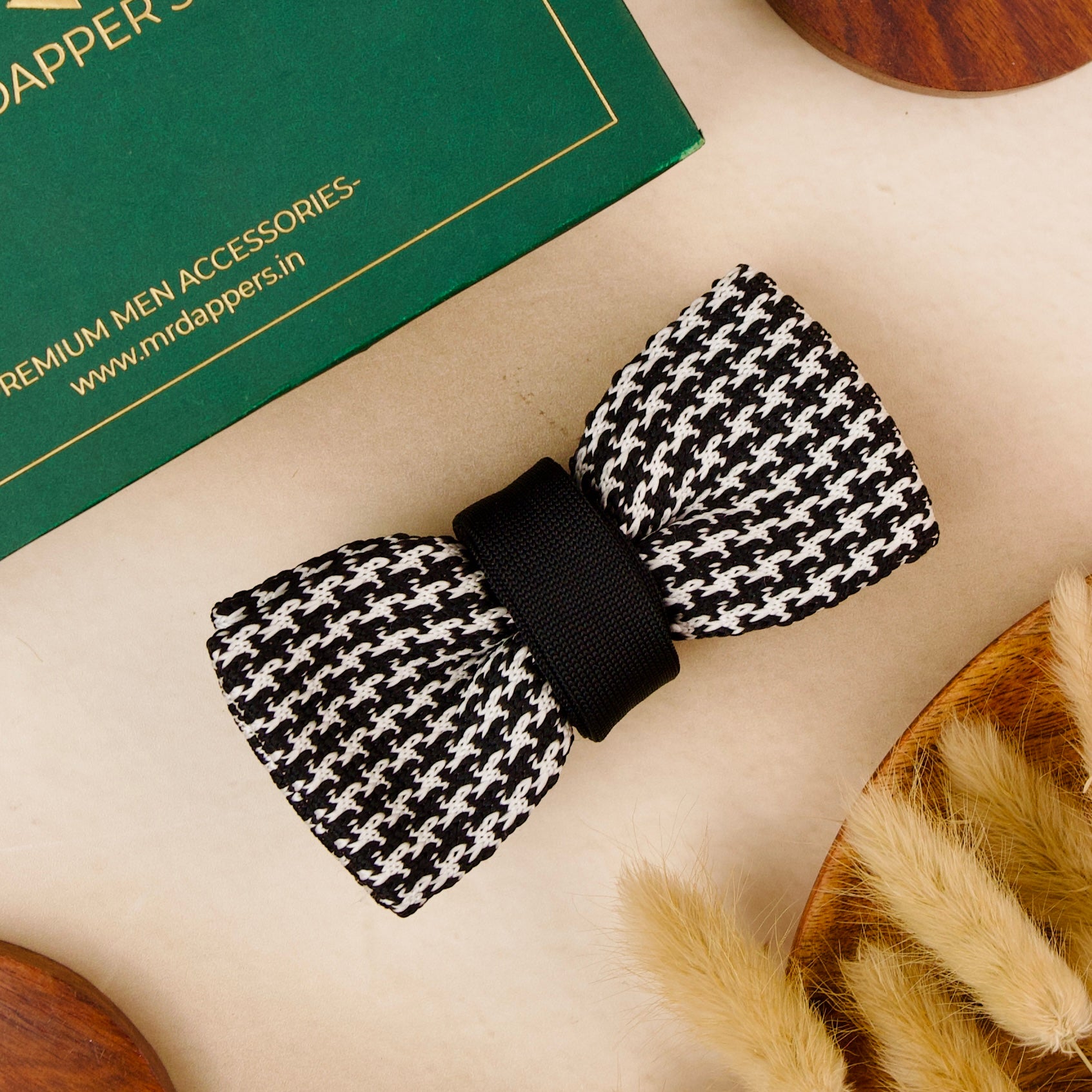  A black and white bow tie elegantly placed on a rustic wooden table, showcasing its classic design and texture.