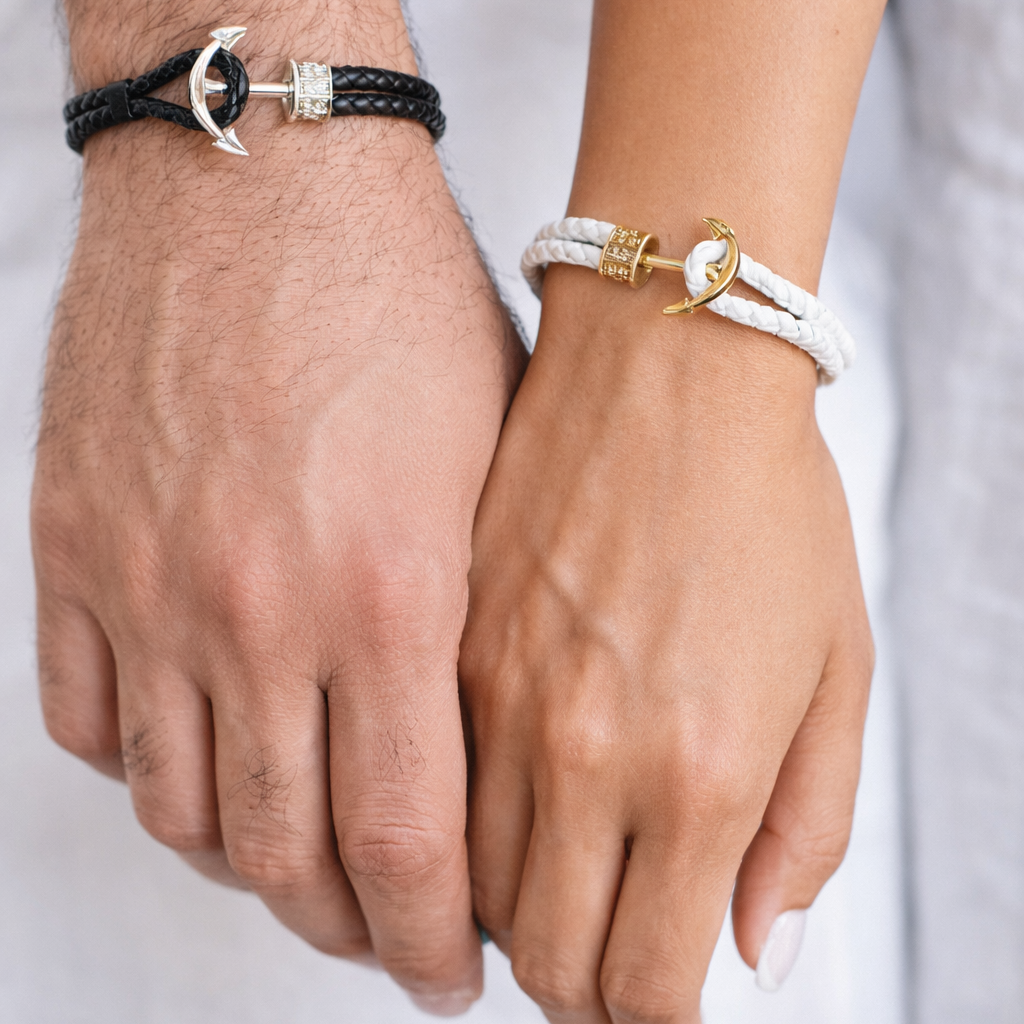 Two hands wearing anchor-themed bracelets on a plain background