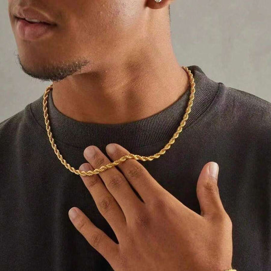 Man wearing a gold chain necklace and bracelet against a neutral background