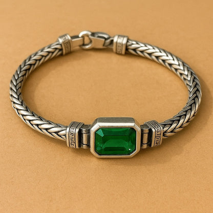 Silver bracelet with a green gemstone on a beige background
