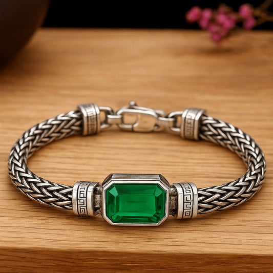 Silver bracelet with a green gemstone on a wooden surface