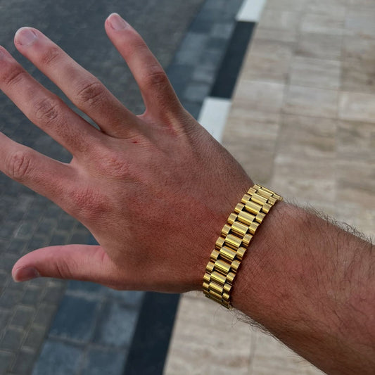 Hand wearing a gold bracelet on a pavement background